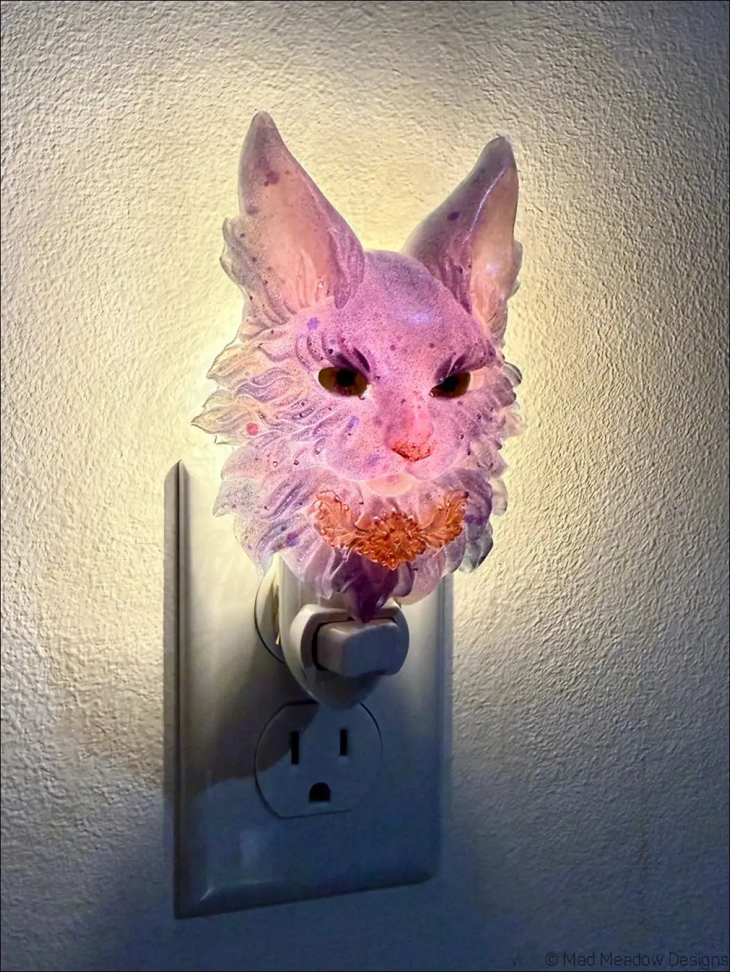 A translucent purple maine coon cat resin wall night light with warm white led bringing whimsical charm plugged in