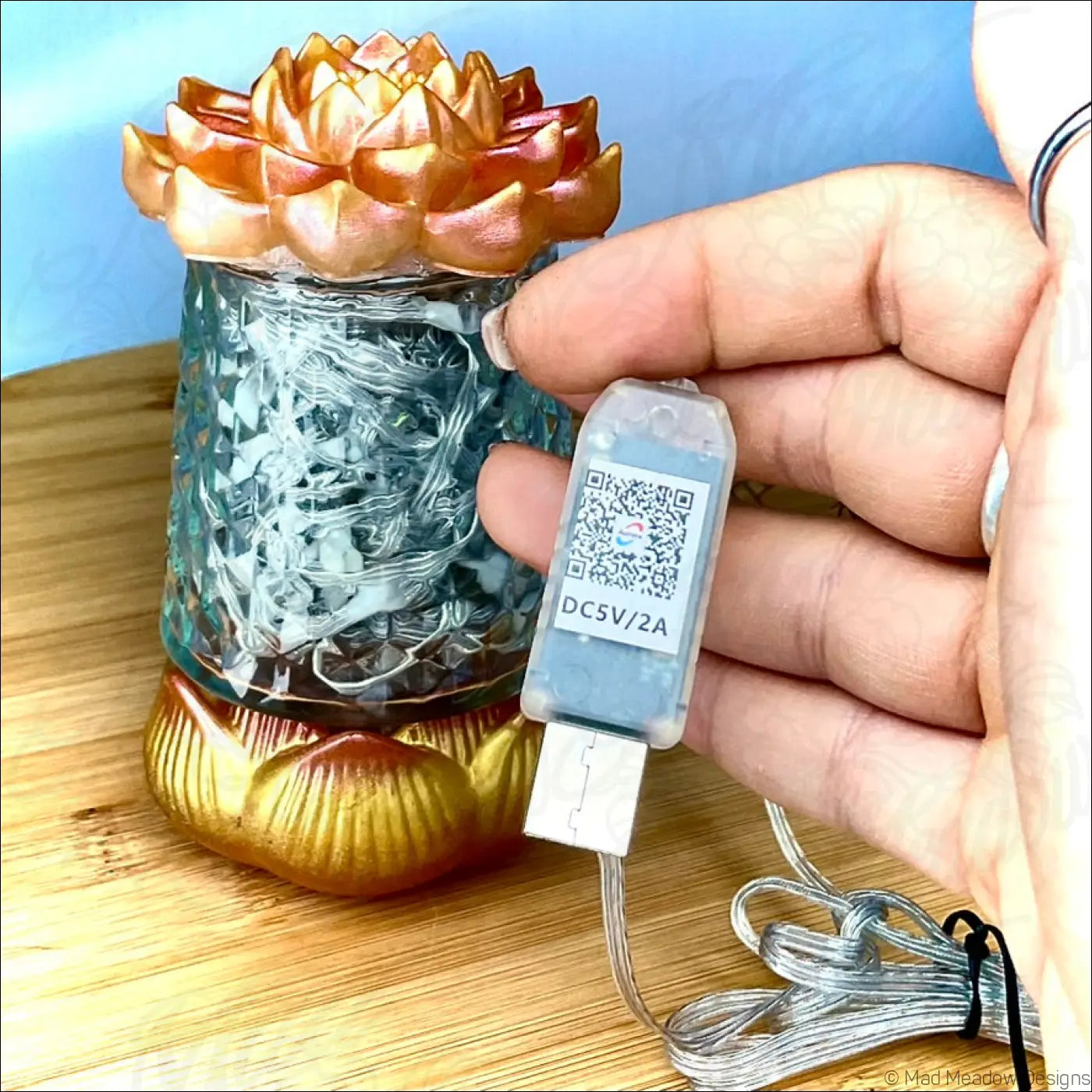 A translucent blue glass lotus flower lantern with gold lotus base and internal wire design app controlled usb light