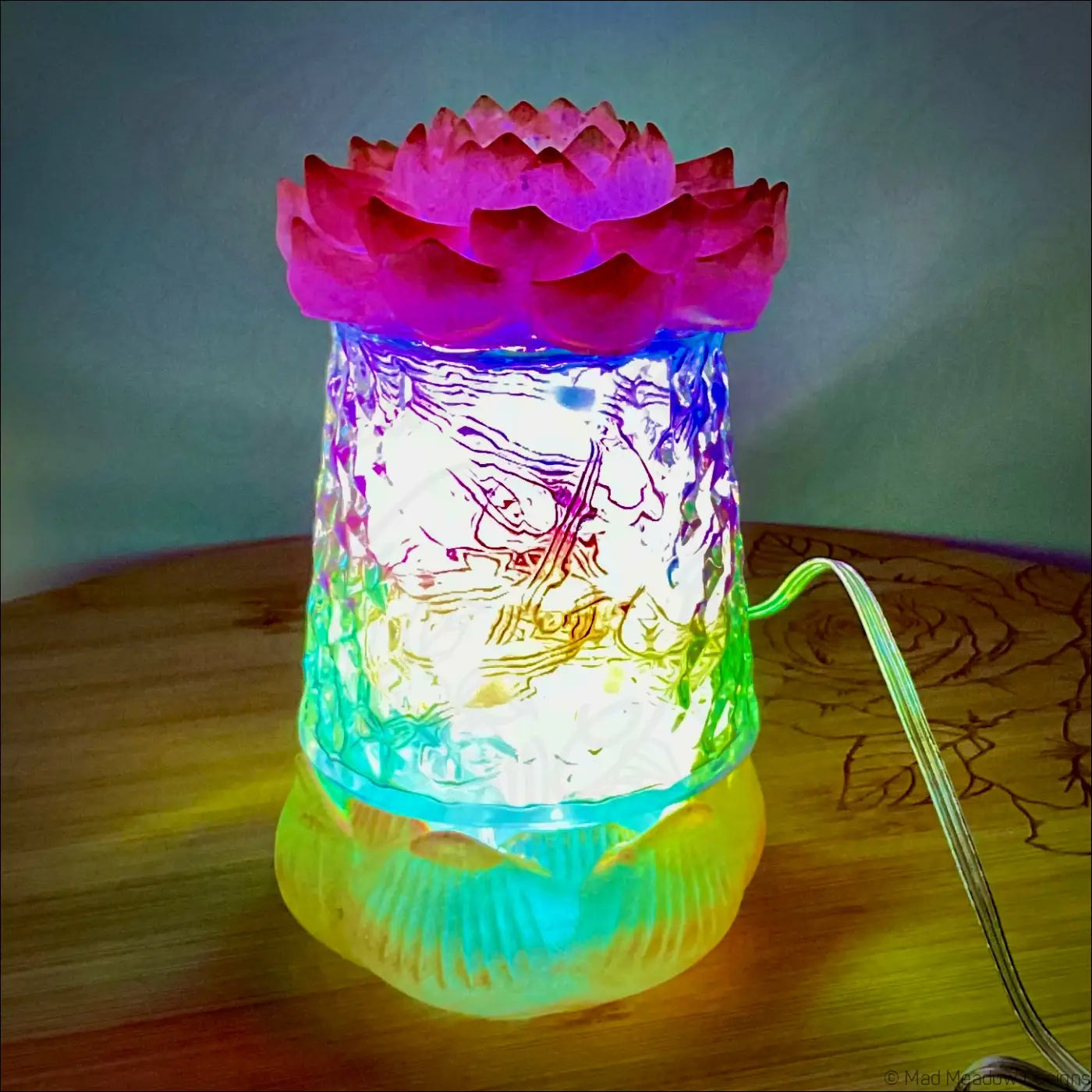 A glowing red pink and gold resin lotus flower glass lamp with intricate carvings and multicolored app controlled led light