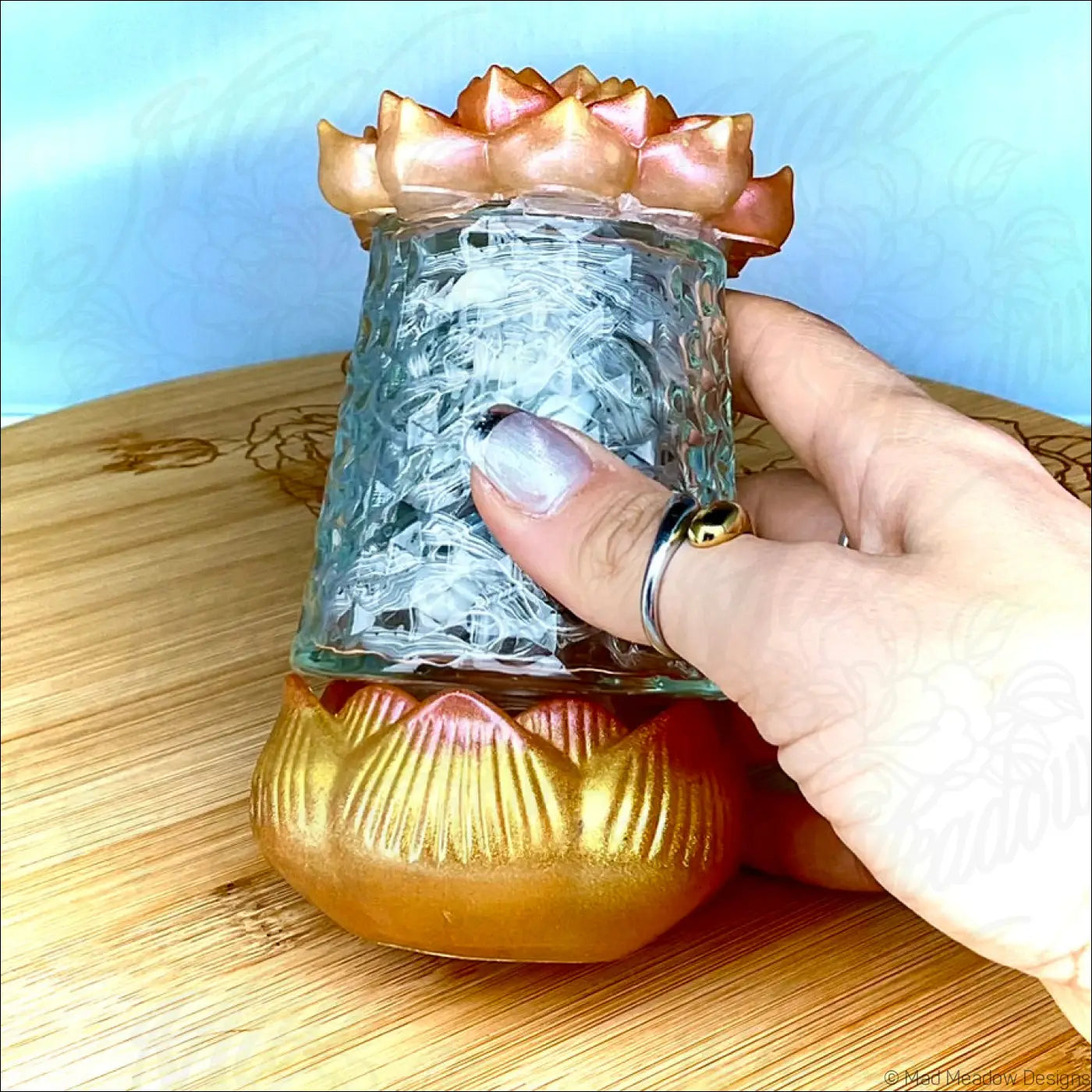 A translucent blue glass candle holder with a crackled surface and gold lotus flower base from a resin lotus usb light