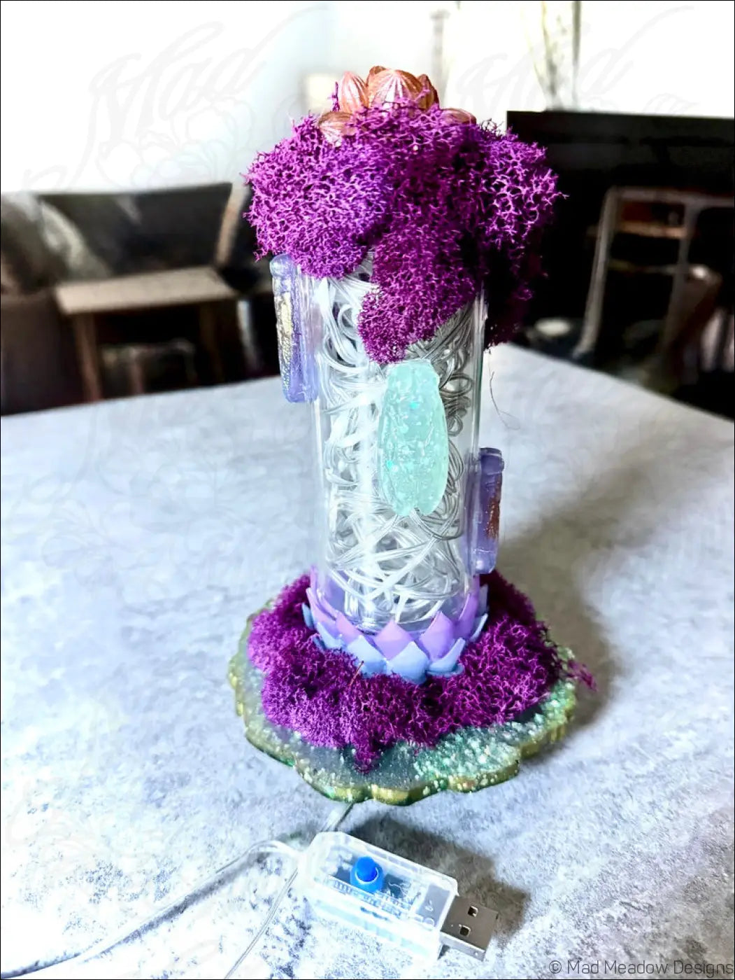 A transparent resin cicadas lamp with a purple floral top and white usb light illuminating string elements