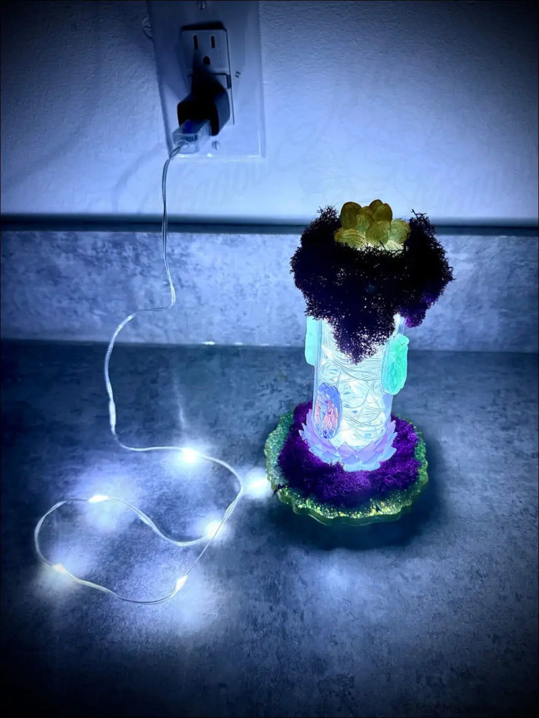 A glowing resin cicadas lantern with a purple green base and white usb light in a vintage glass bottle design