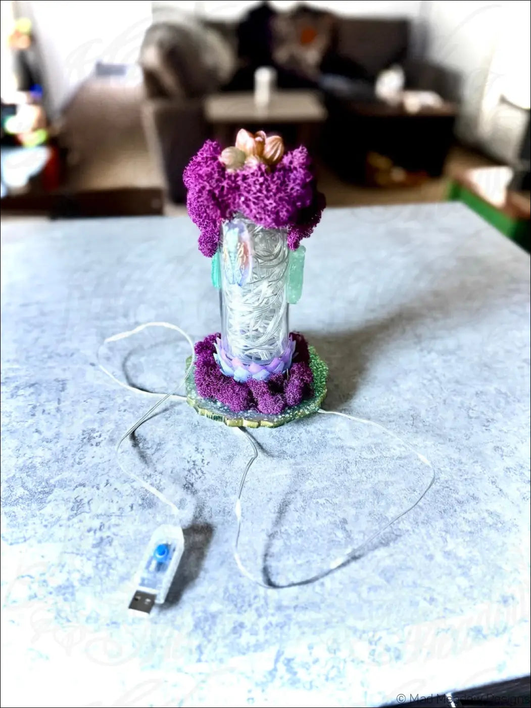 Purple textured resin cicadas centerpiece with glass cylinder and green base featuring white usb light