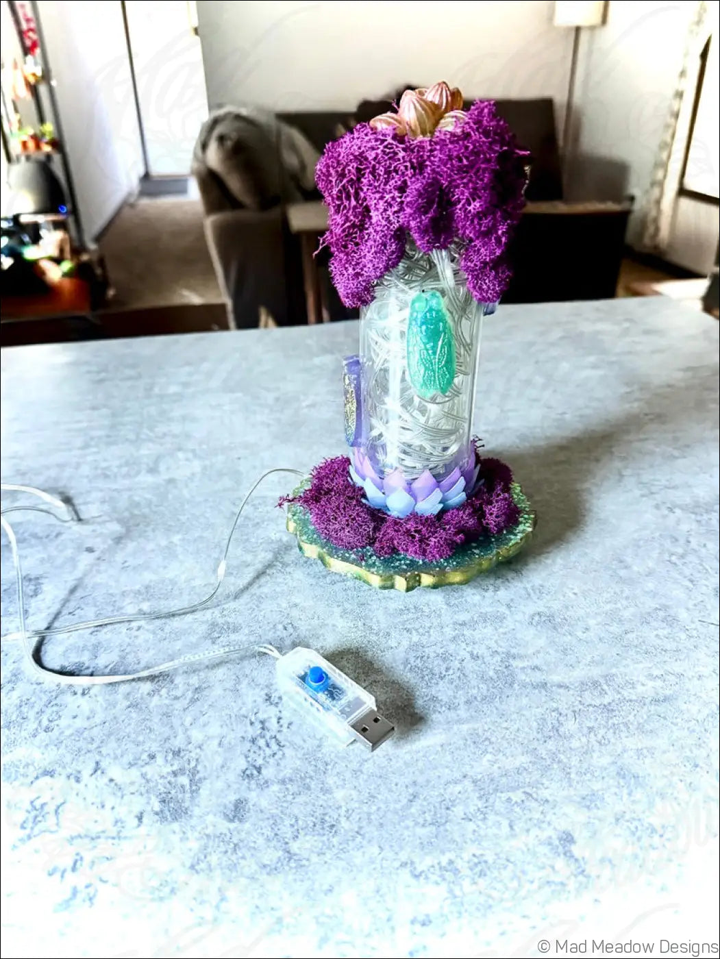 A resin cicadas vintage glass lantern with purple moss top base teal leaf design and white usb light inside