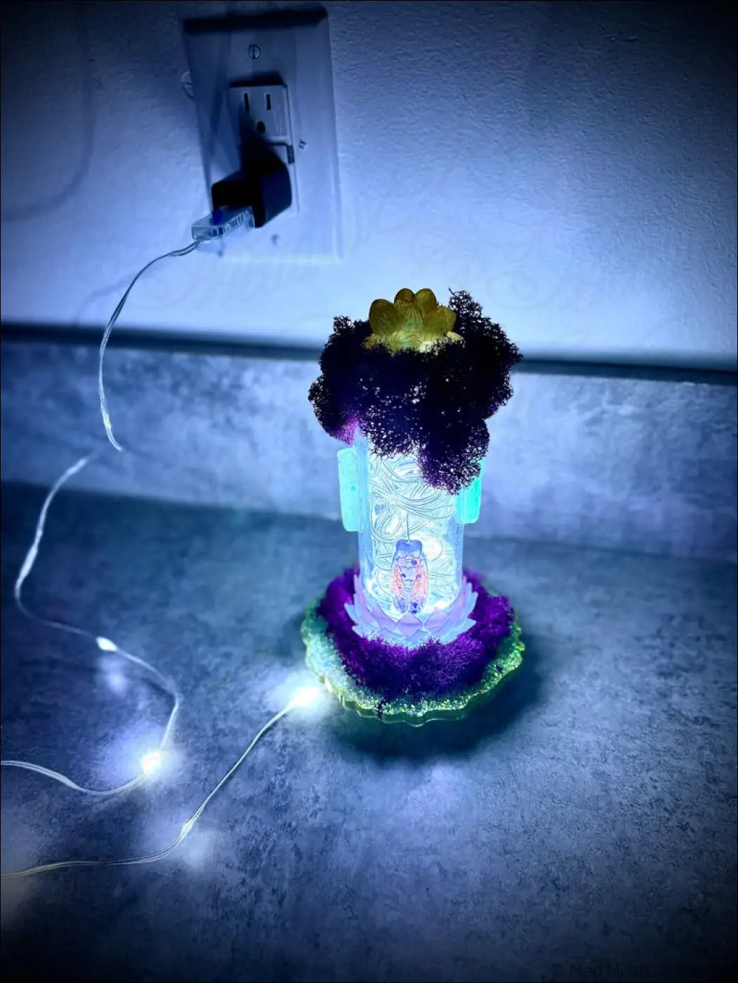 A glowing resin cicadas vintage glass bottle with white usb light featuring a purple green base and moss-like top