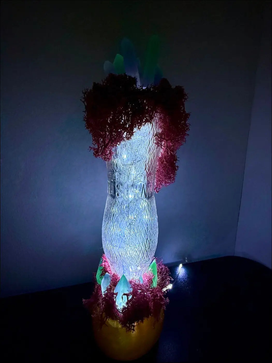 A glowing translucent glass vase with etched patterns and blue light inside in a 1920s hourglass whistle soda vintage style