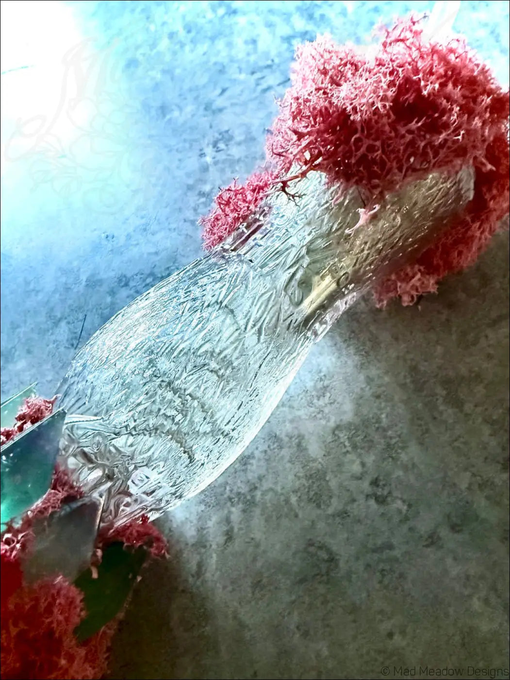 A clear textured glass perfume bottle with silver cap and red coral accents inspired by 1920s hourglass whistle soda