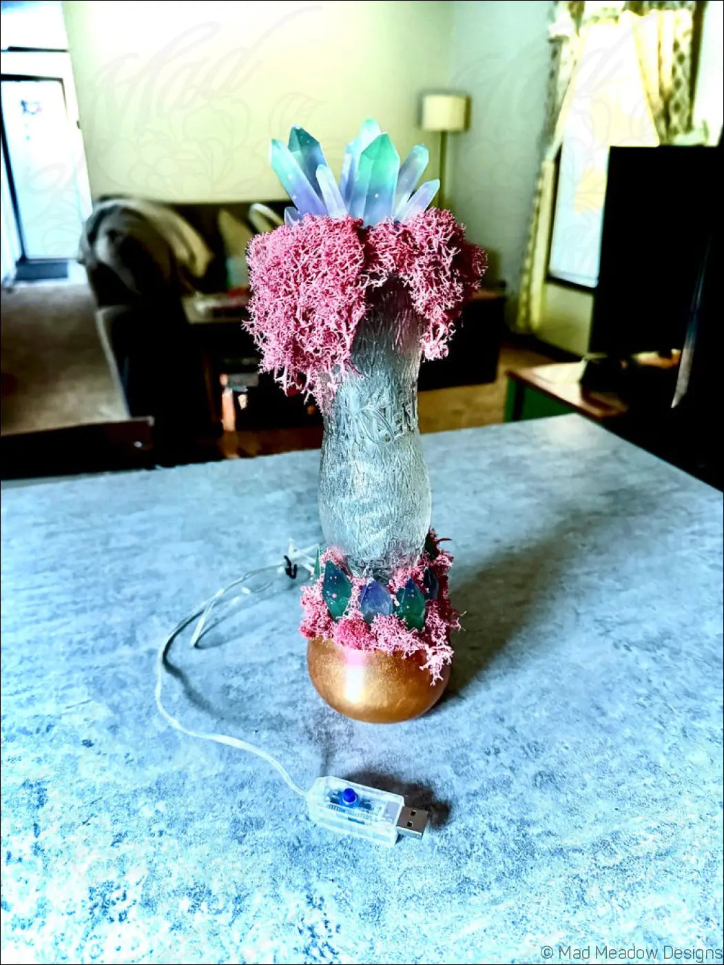 A glowing resin crystal lamp with pink moss accents and copper base inspired by 1920s hourglass whistle soda vintage style