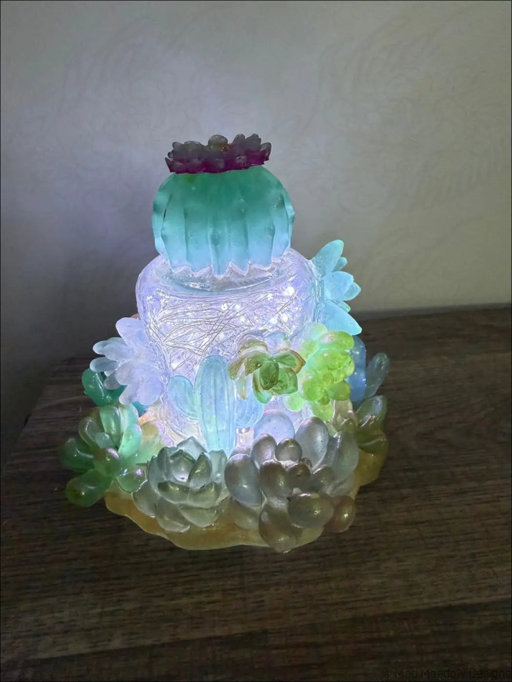 A glowing multi-tiered succulent garden light with teal green and purple resin cactus shapes usb powered