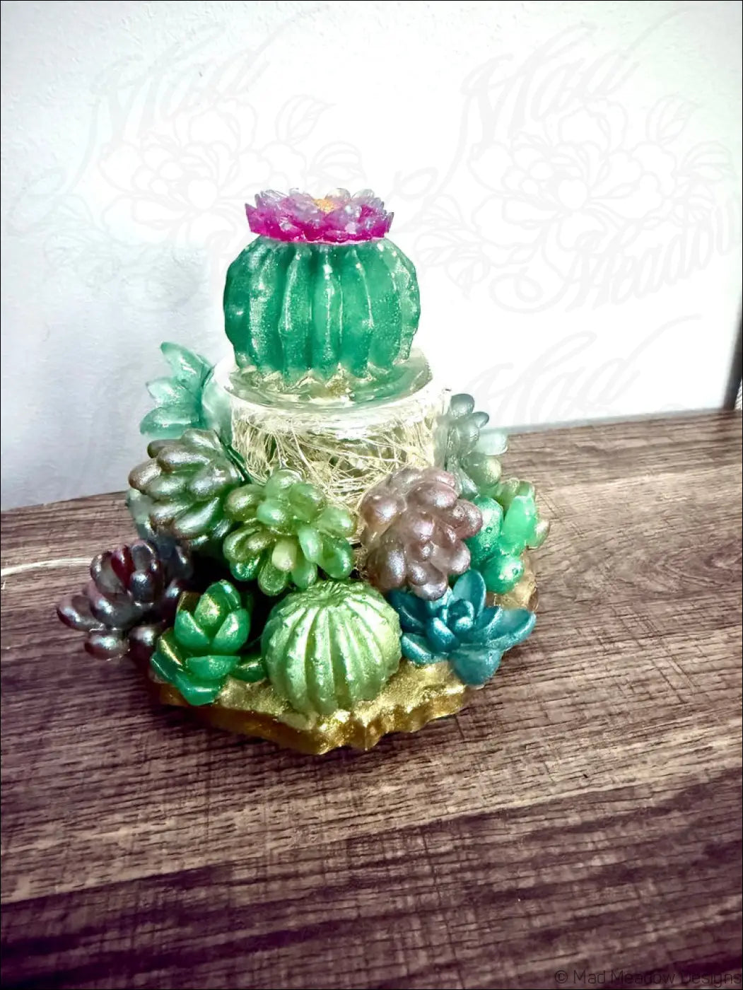 A usb powered succulent garden light with tiered translucent green resin and a pink flower on a gold base