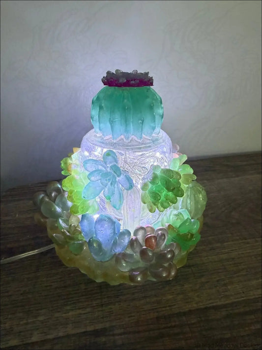 A translucent multi tiered glass cactus lamp with glowing succulents and purple gemstone top usb powered succulent garden light