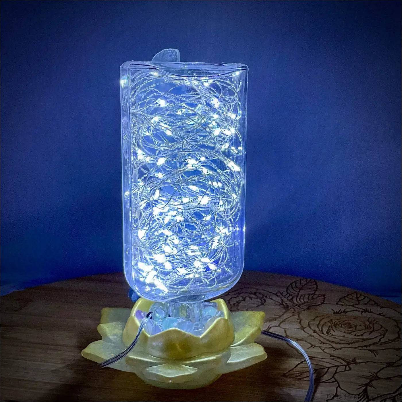 A translucent antique glass apothecary bottle filled with glowing white fairy lights on a golden lotus base usb light