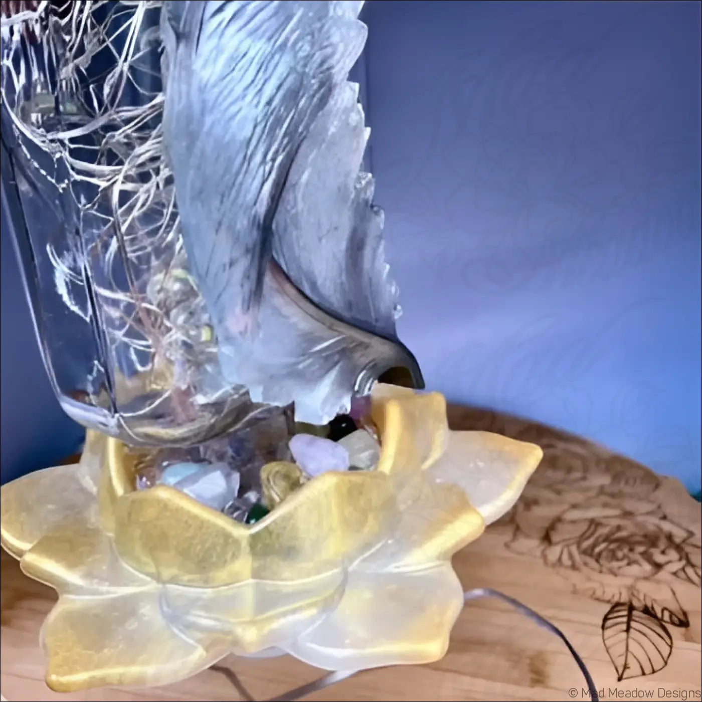 Silver feather glass apothecary bottle with translucent carved wing on golden lotus base filled with smooth stones