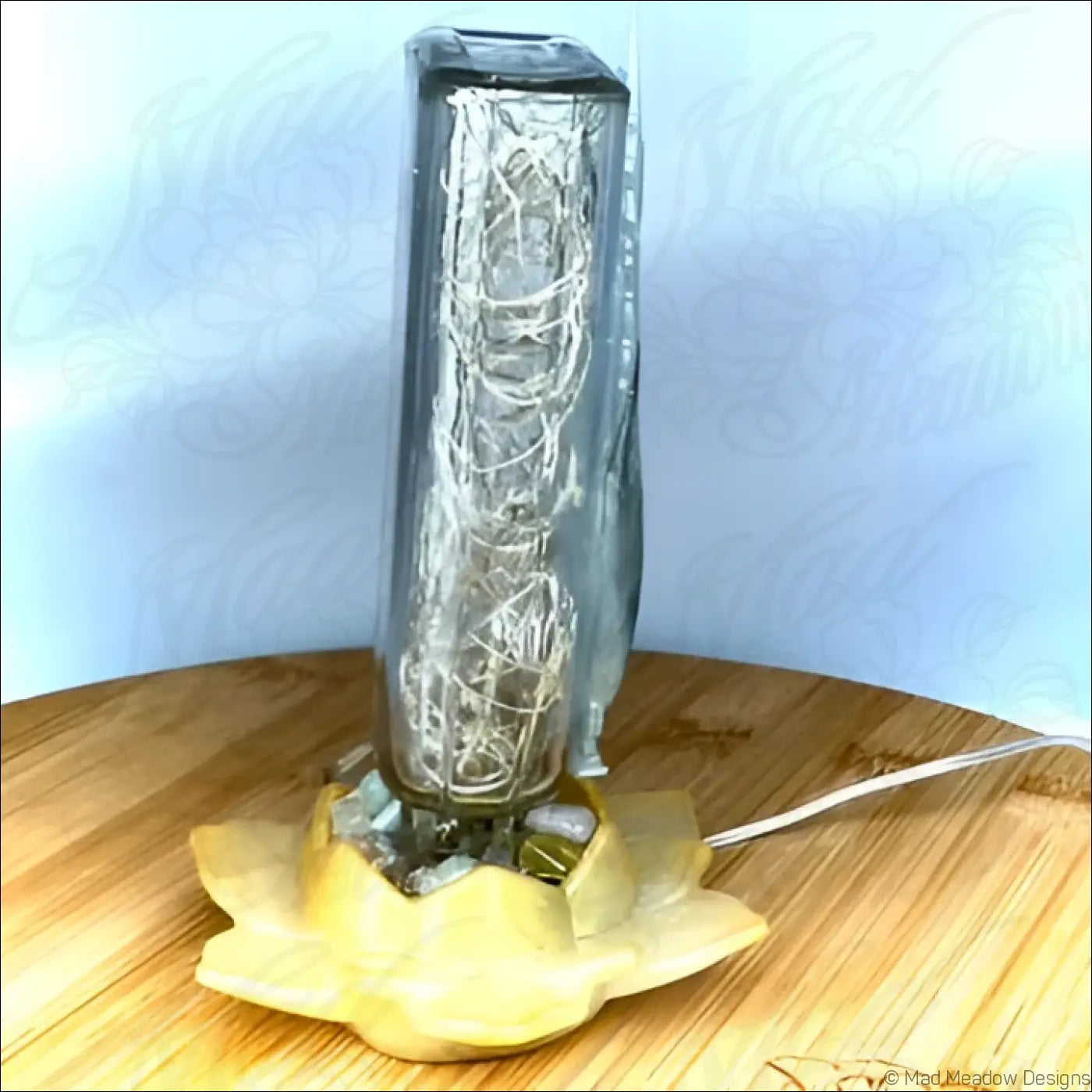 Silver feather usb light with intricate silver wirework in an antique glass apothecary bottle on a yellow lotus base
