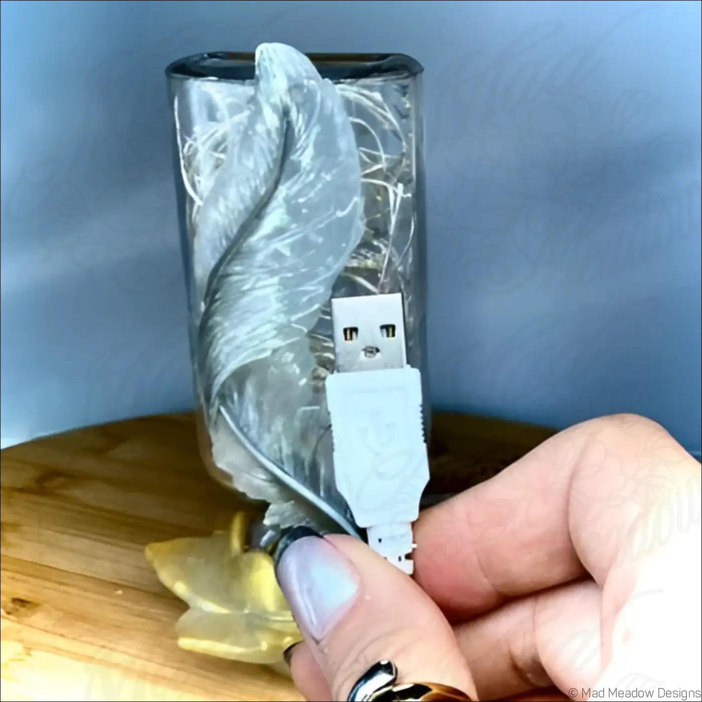 White usb-a to micro-usb charging cable with matte finish held by hand near antique glass apothecary bottle