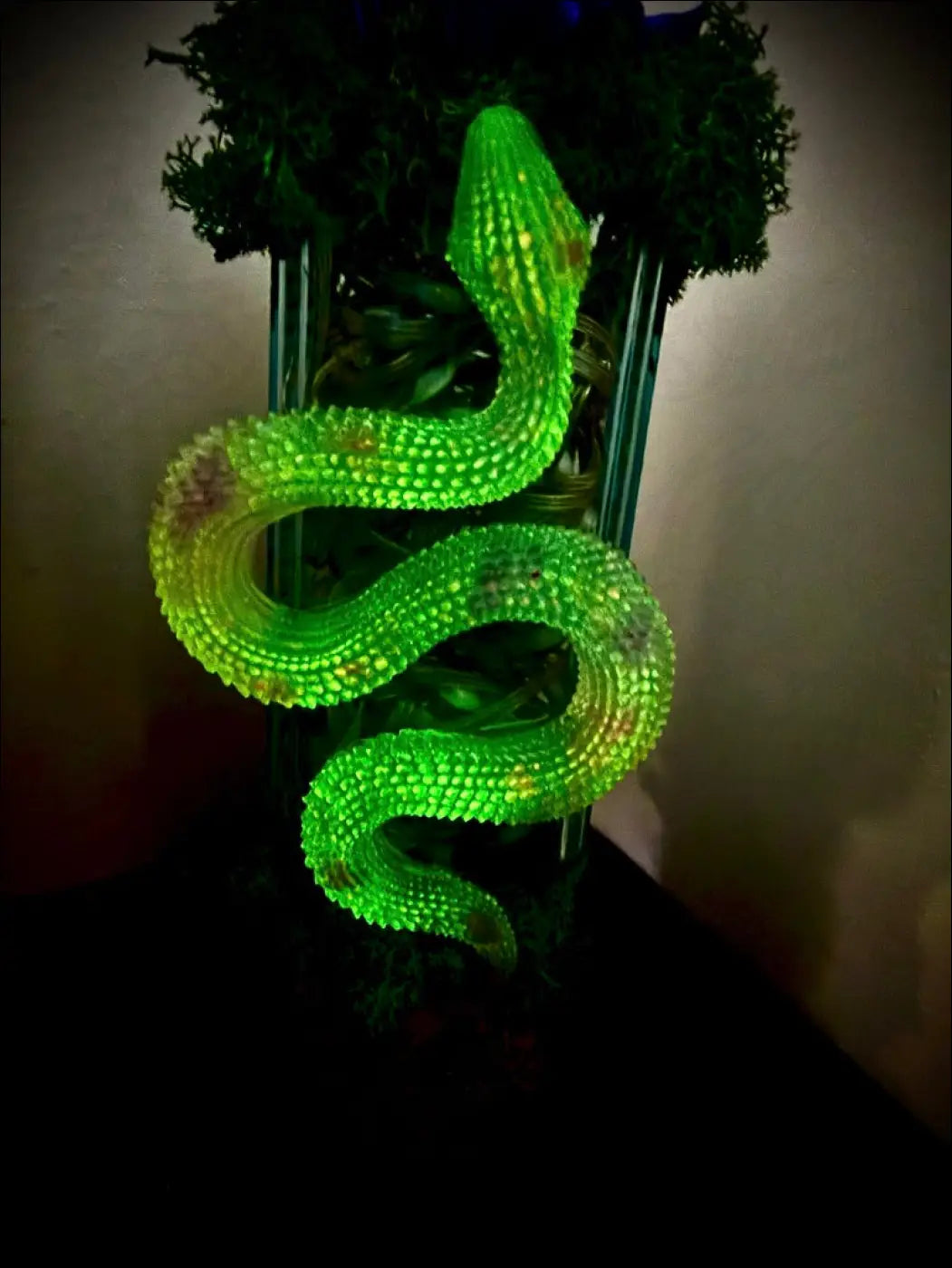 A glowing neon green snake sculpture with a textured segmented body coiled around a glass apothecary bottle usb light