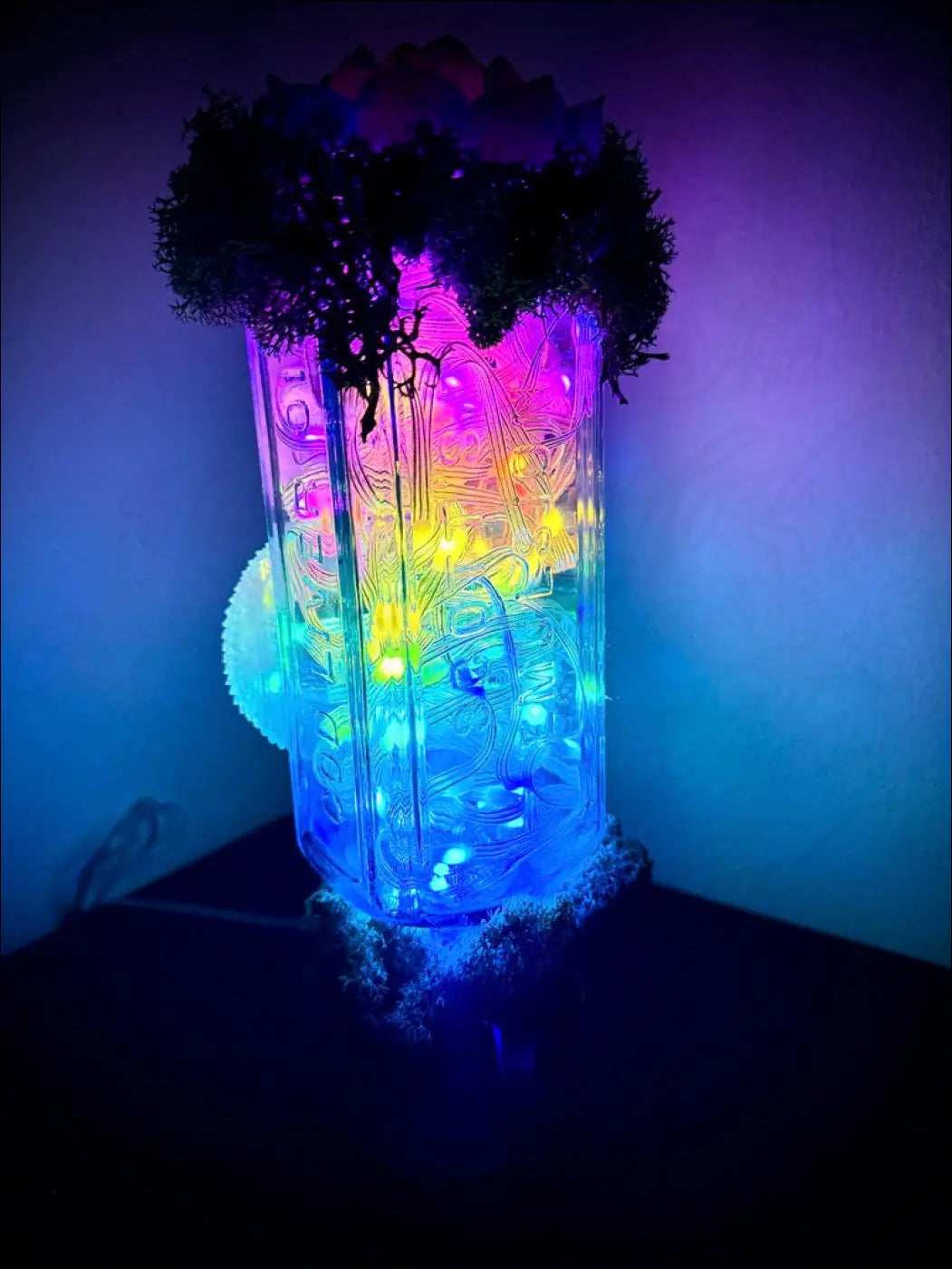 A glowing translucent glass lantern with etched designs and multicolored leds on a snake and lotus usb light