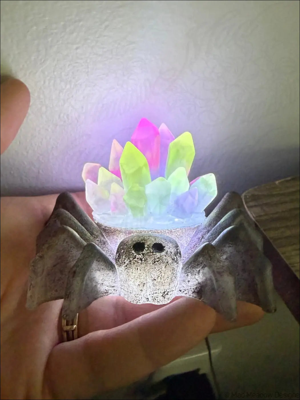 A glowing gray spider-shaped led nightlight with textured surface and colorful crystal spikes on its back usb powered