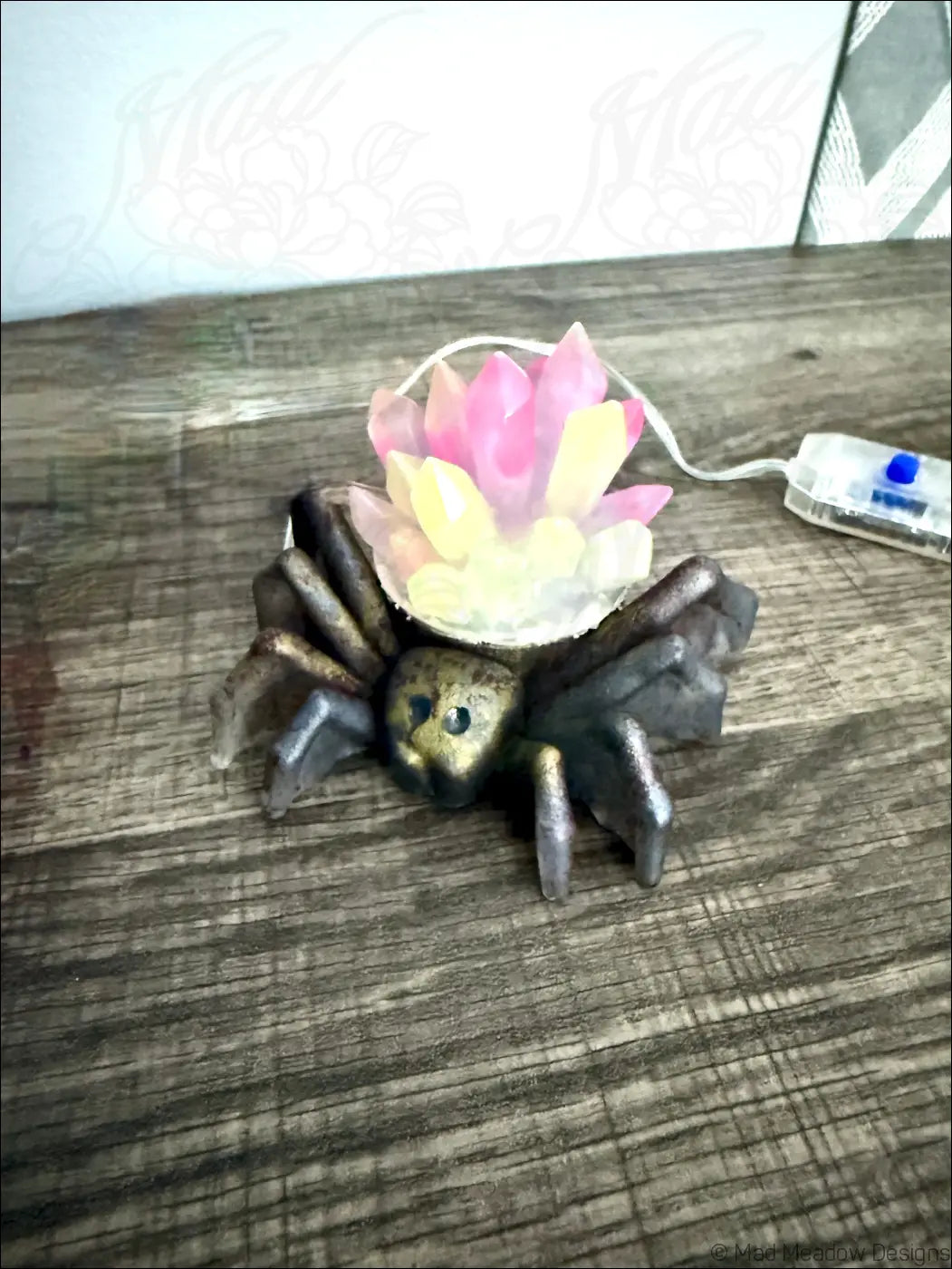 A whimsical spider crystal light usb lamp with metallic bronze finish and glowing pink and yellow succulent flowers