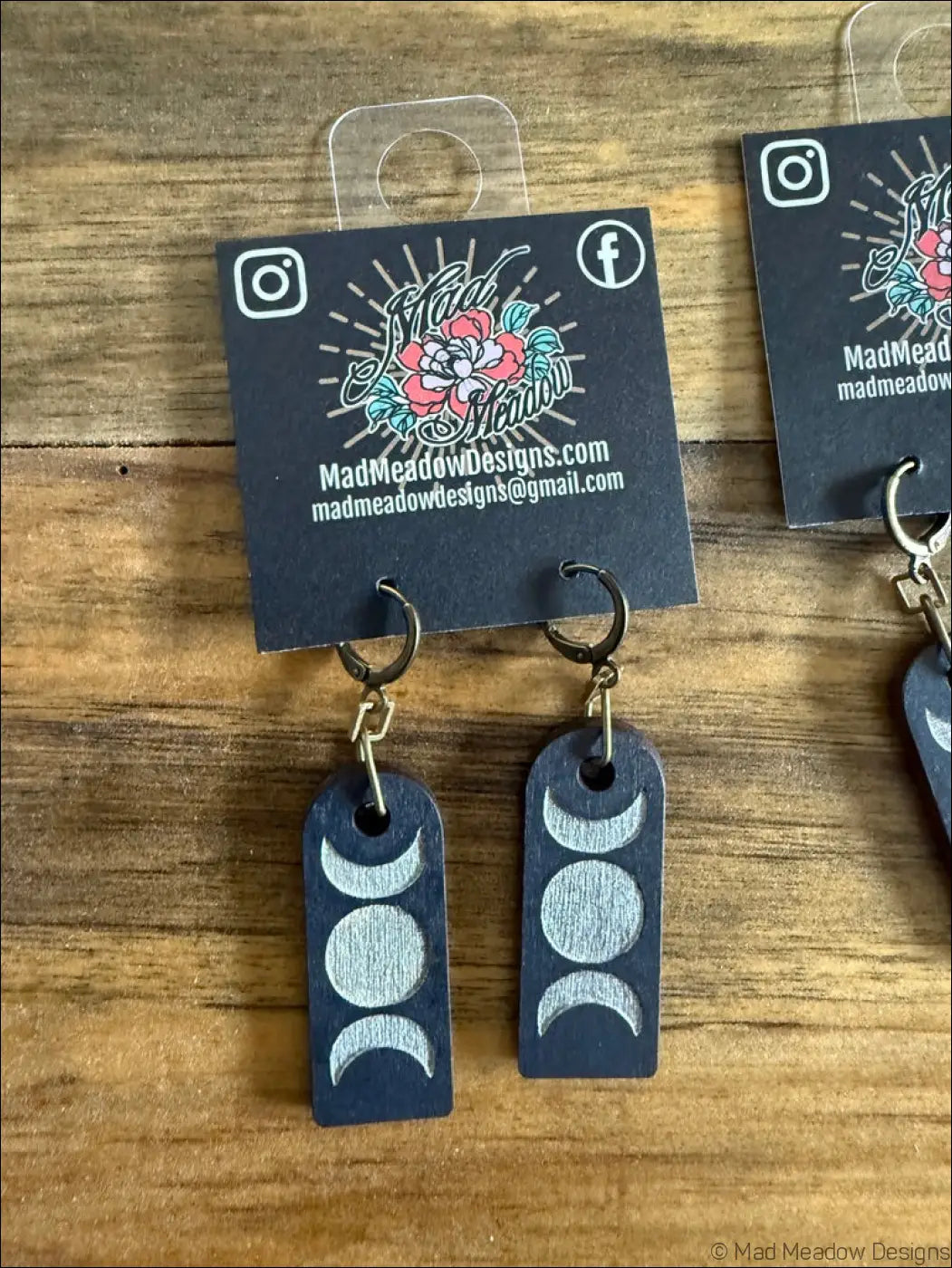 Dark blue wooden earrings with silver triple moon hand-painted designs in a rectangular shape