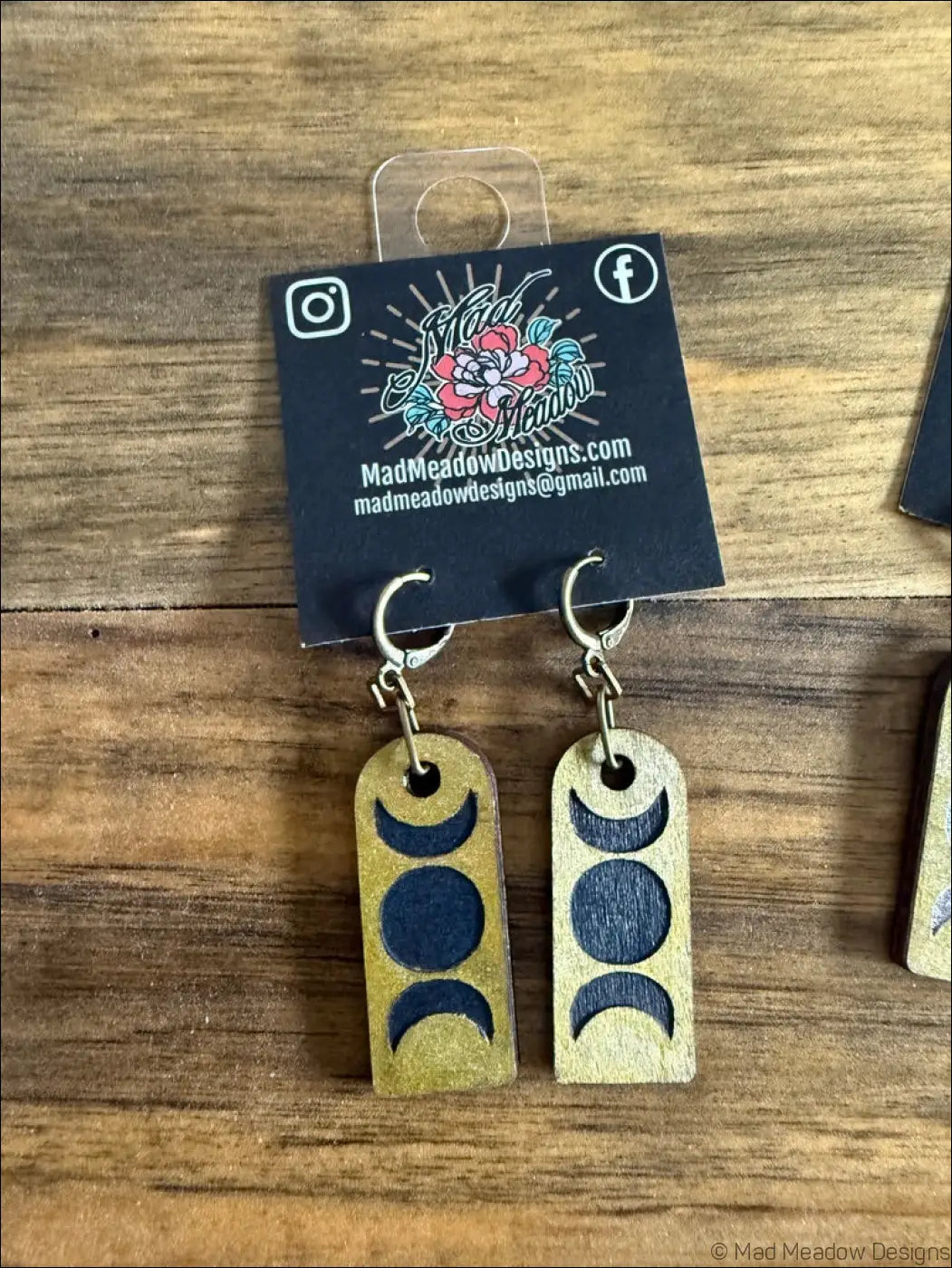 Gold-finished wooden triple moon earrings with dark blue moon phases on rectangular pendants and silver hooks