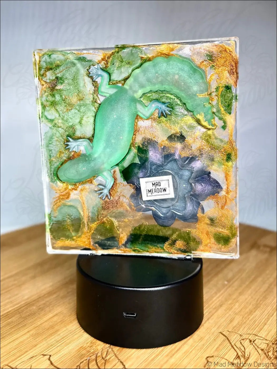 A captivating green gecko figurine in colorful resin with swirling greens and golds in a water lily nightlight