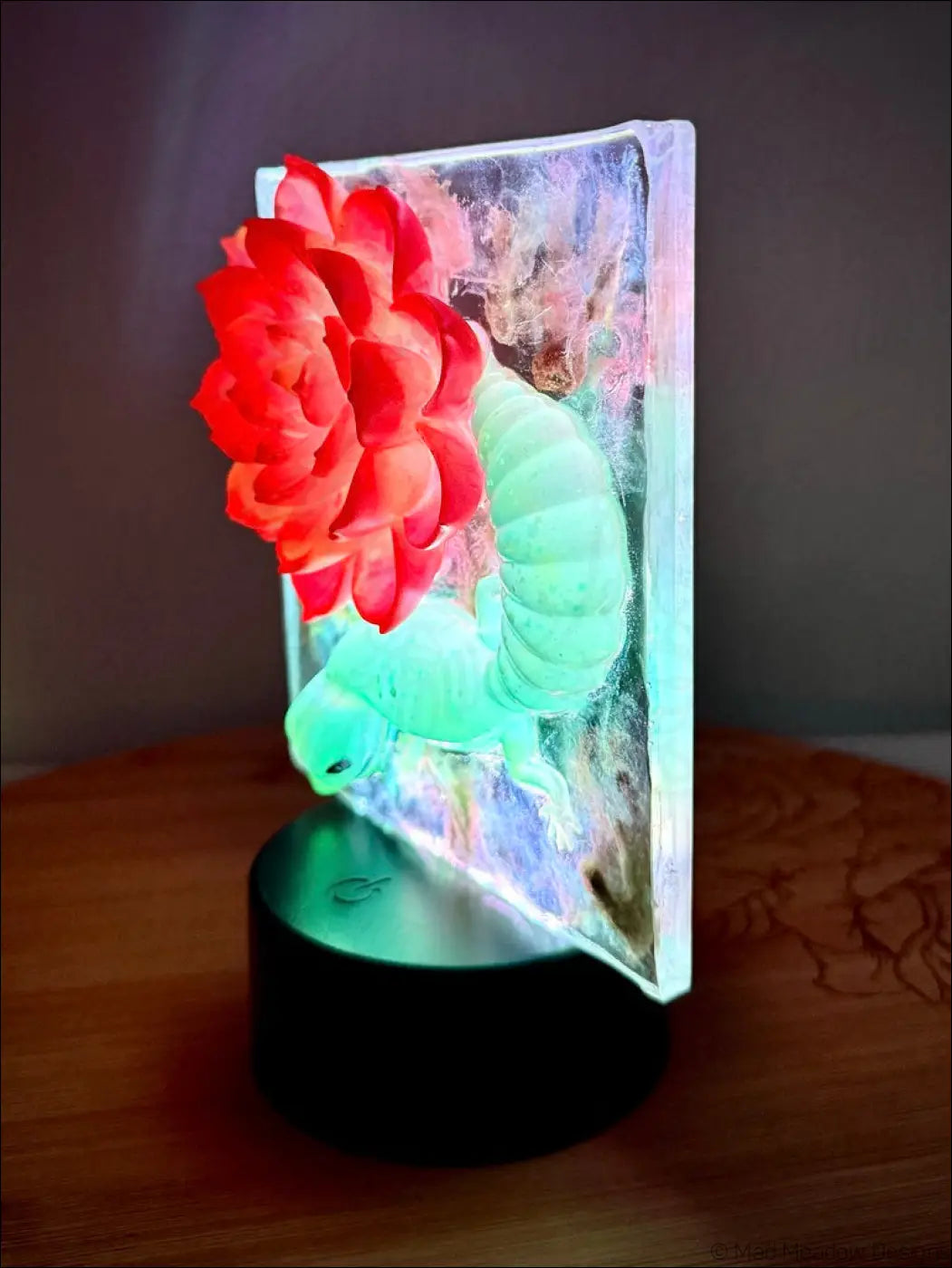 Whimsical glowing gecko night light with vibrant crimson bloom and translucent green caterpillar on black base