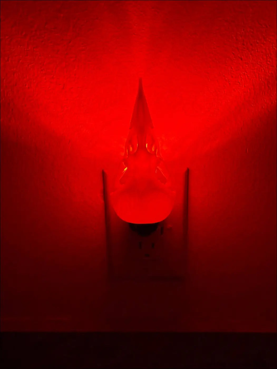 A glowing red pointed glass white bird skull wall night light adding whimsical wonderland vibes at night